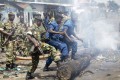 Des militaires et des policiers poussent de leur pieds un tronc d'arbre pour dégager une barricade érigée par des manifestants ans le district de Cibitoke, à Bujumbura, Burundi, lundi 25 mai 2015