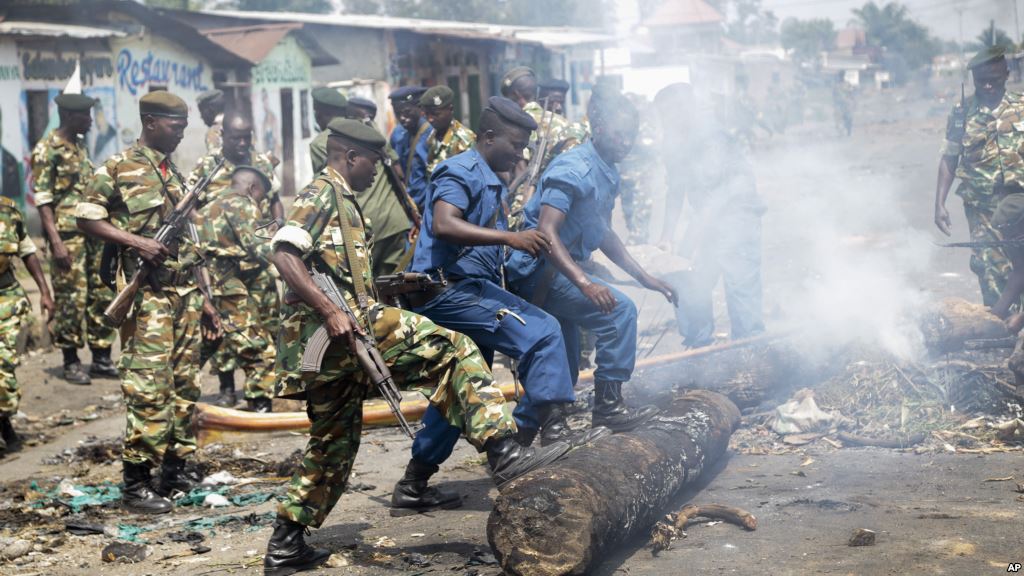 Des militaires et des policiers poussent de leur pieds un tronc d'arbre pour dégager une barricade érigée par des manifestants ans le district de Cibitoke, à Bujumbura, Burundi, lundi 25 mai 2015