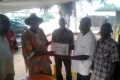 Dr Djobo Anvra Jeanson, le chef du village de Songon M’Brathé (en tenue traditionnelle et chapeau), recevant le diplôme d’honneur des Journalistes des mains de Laurent Nahounou, président de Journalistes Volontaires pour la Paix et la cohésion sociale (à droite, chemise blanche).